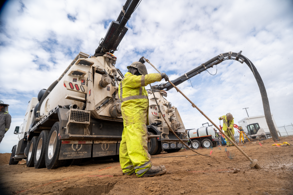 Hydrovac truck and crew performing vacuum excavation at an active job site.