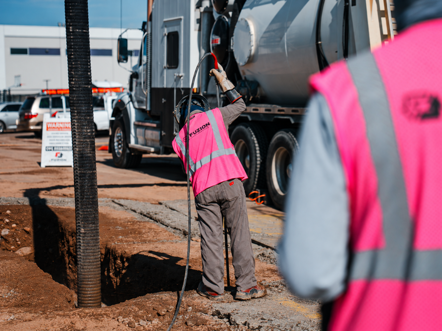 Fuzion crew performing hydro excavation beside a vacuum truck.