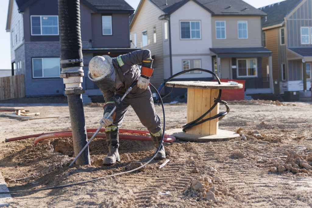 Fuzion worker hydrovacing underground utility lines at a residential construction site.