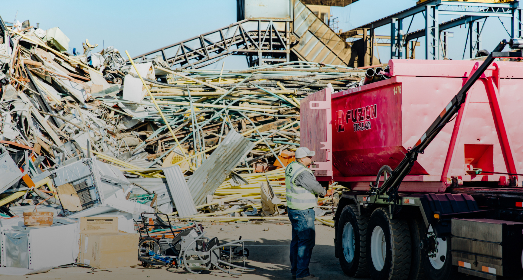 A large dumpster from Fuzion at a scrap metal yard.