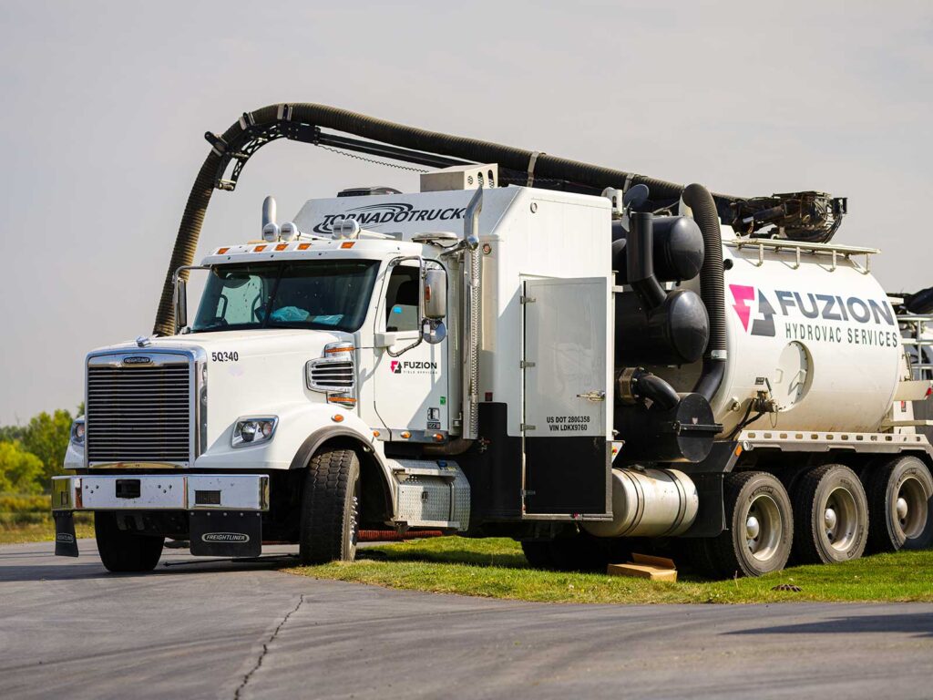 Fuzion Hydrovac truck parked at an oilfield site on a clear day.