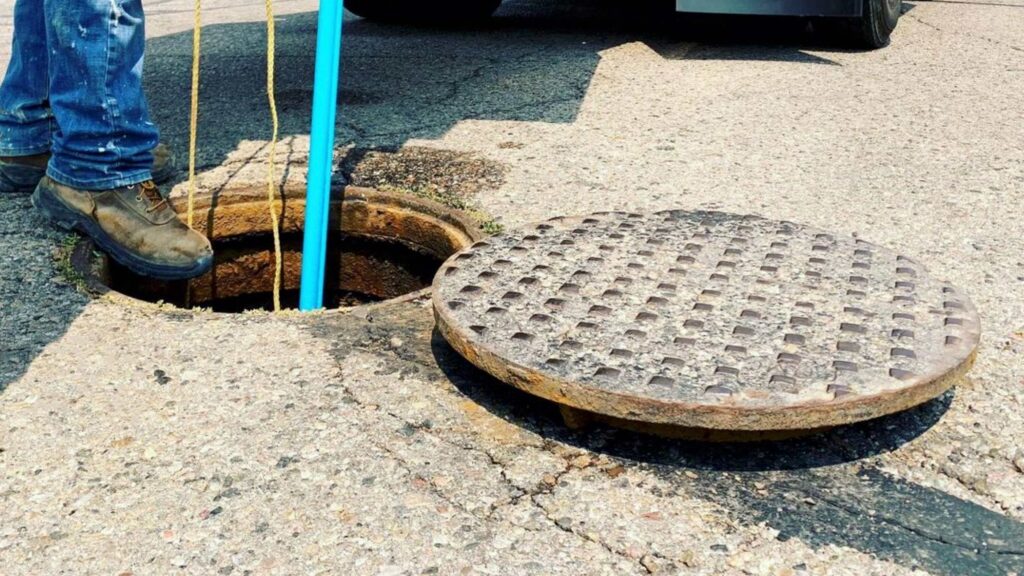 Worker inserting line jetting hose into a manhole.