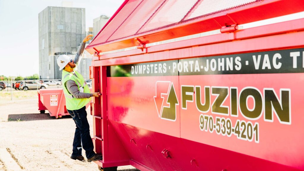 Worker standing on the side of a 15-yard dumpster rental.