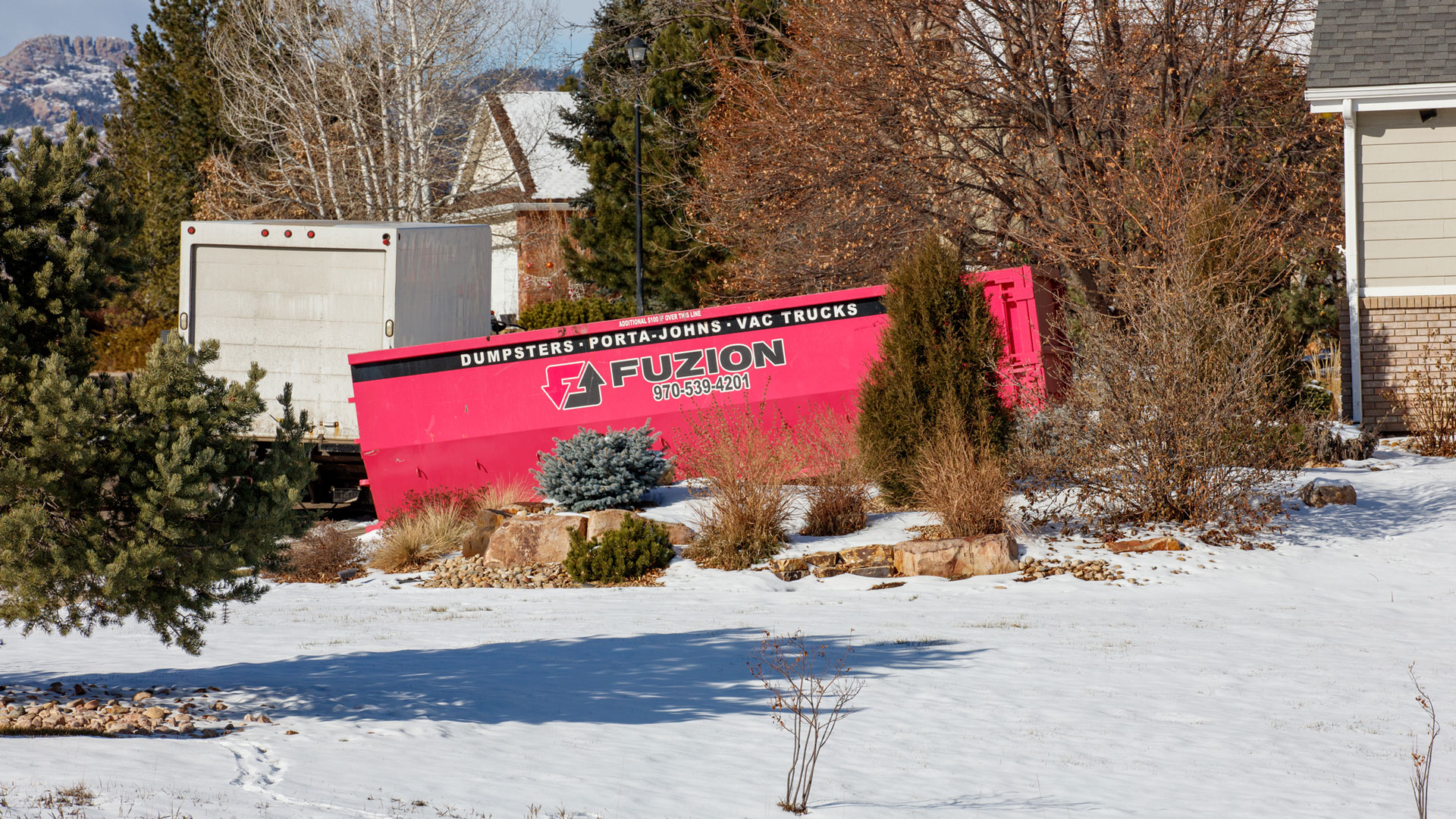 Fort Collins dumpster rental in a driveway with Horsetooth Rock in the background.