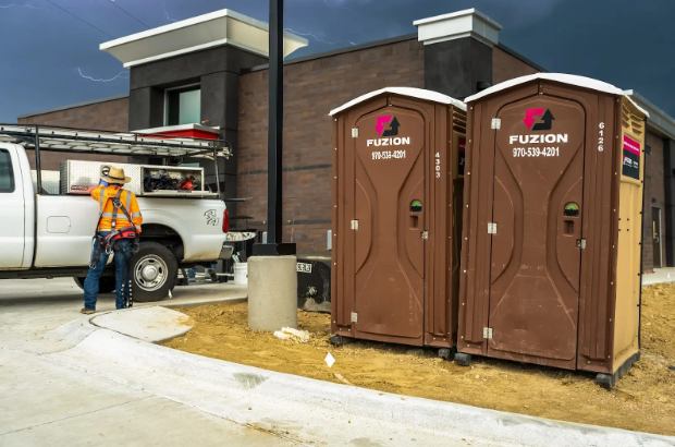 Fuzion portable toilets with construction equipment in the background.