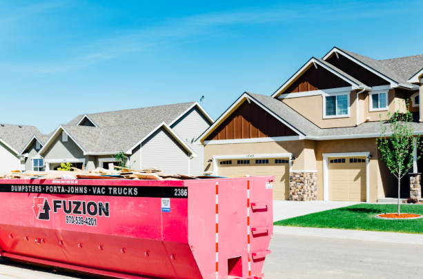Large pink Fuzion dumpster placed in front of a residential home.