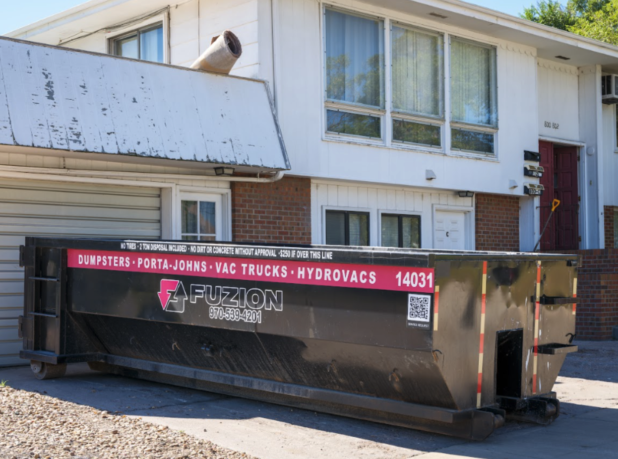 Black Fuzion dumpster outside a home undergoing roof replacement.