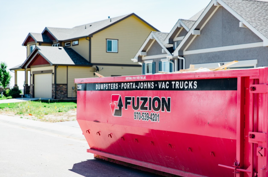 Bright pink Fuzion dumpster placed in front of suburban homes under construction.
