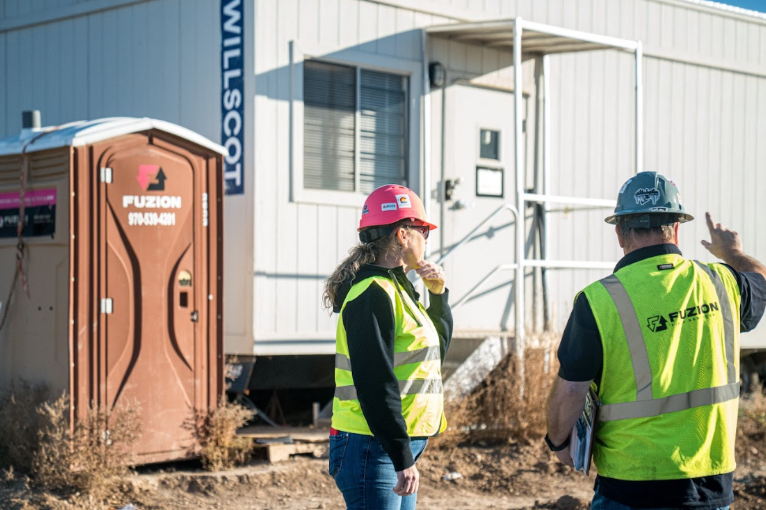 Two Fuzion workers talk outside a site trailer.