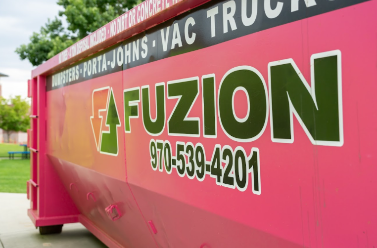Close-up of a pink Fuzion dumpster with the company logo and phone number.
