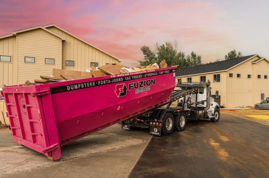 A Fuzion dumpster sits beside an apartment building, ready for debris removal during an apartment turnover.