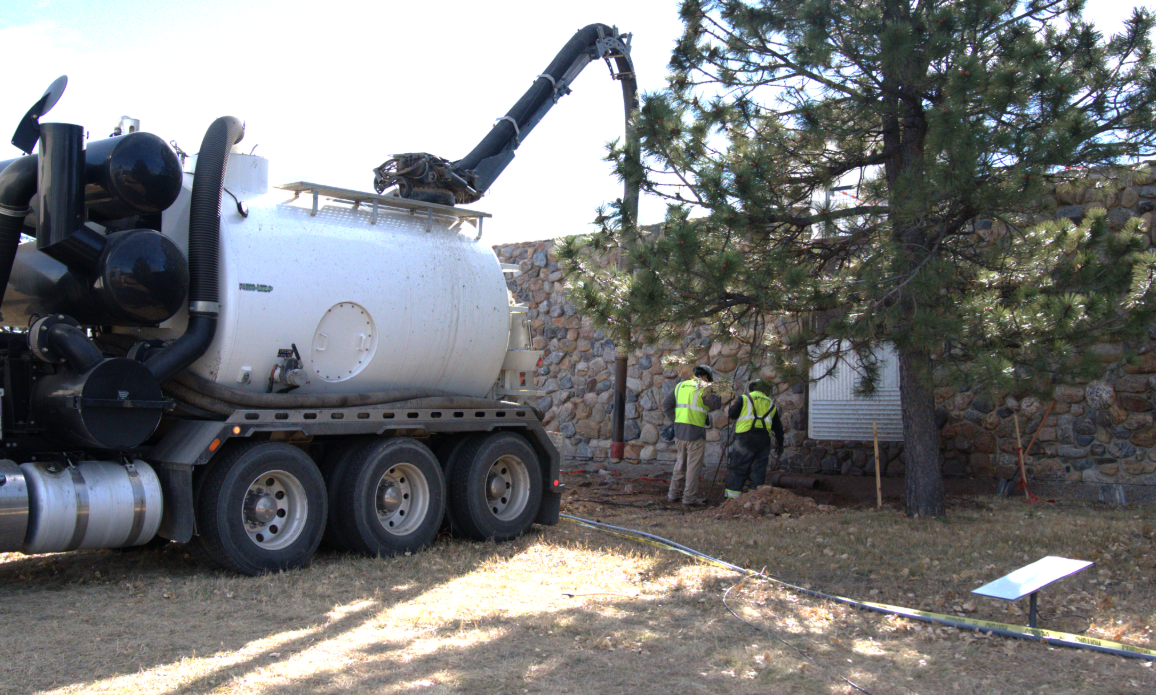 Vacuum excavation truck and crew working near underground pipes during hydrojetting vs snaking service evaluation.