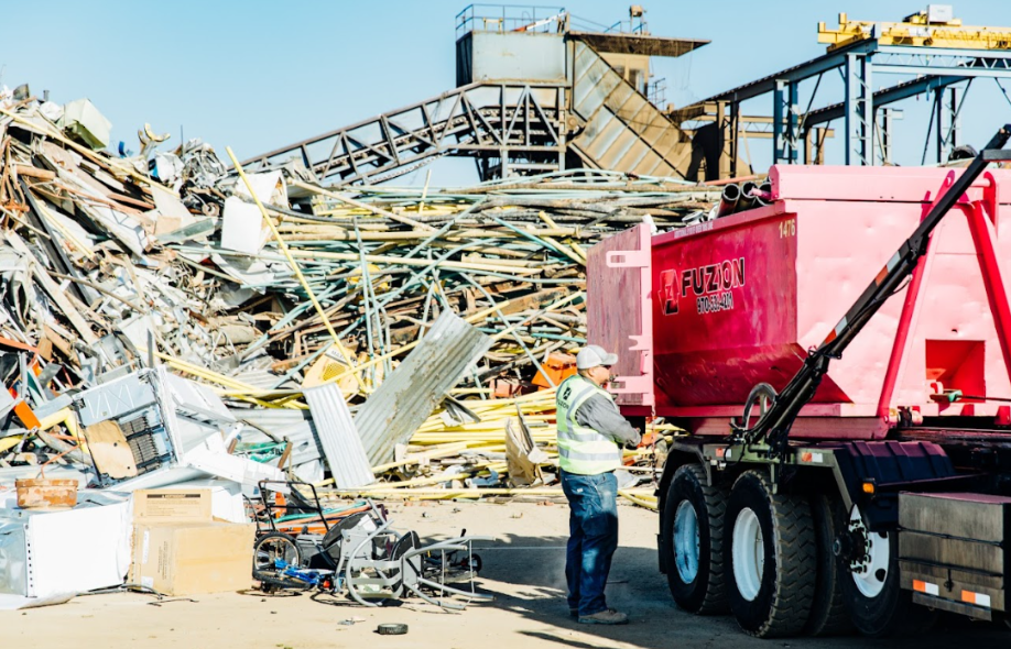 Worker unloading a Fuzion dumpster at a recycling site to support landfill diversion.