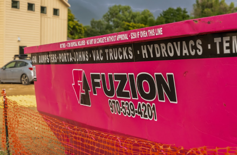 Pink Fuzion disposal dumpster on a job site used for foreclosure clean outs.