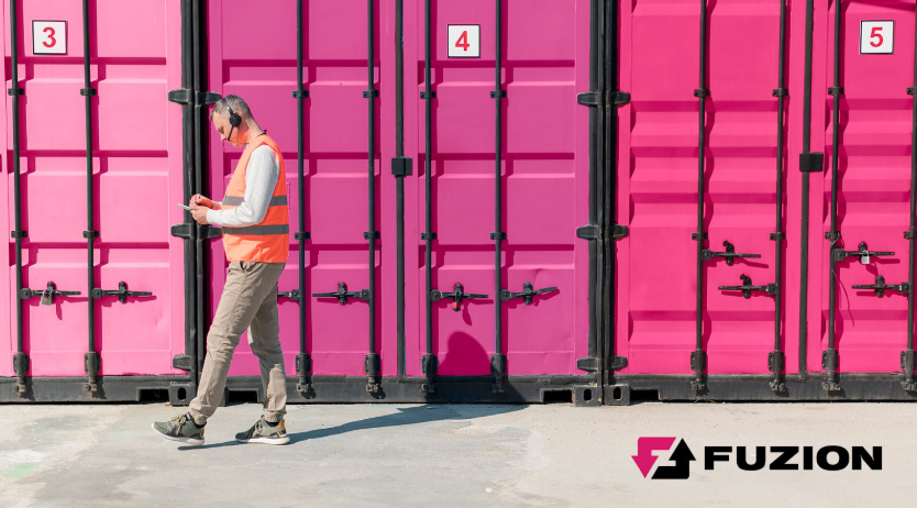 Worker walking past pink storage containers at a storage container rental site.