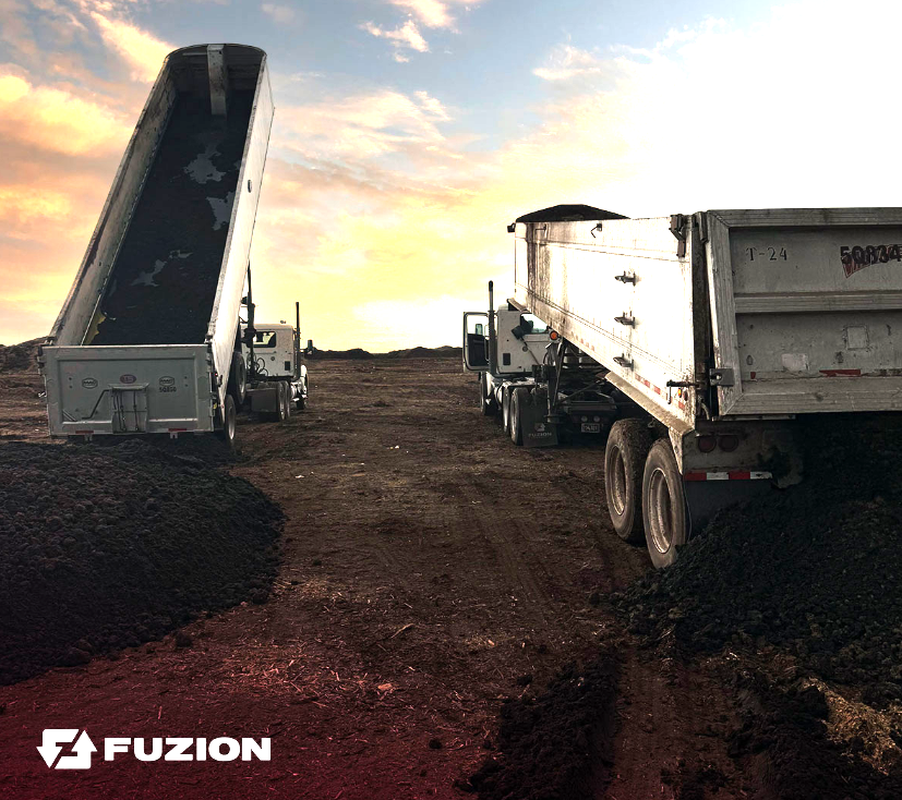 Dump trucks unloading organic material at a work site, illustrating what is organic waste.