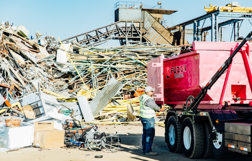 Worker sorting construction debris to highlight compost vs landfill disposal options at an industrial site.