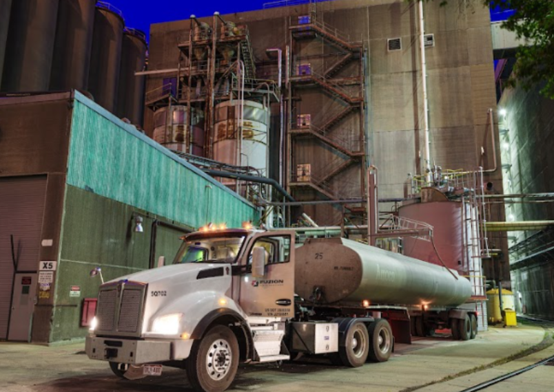Fuzion tanker truck performing industrial water tank cleaning at a large industrial facility.