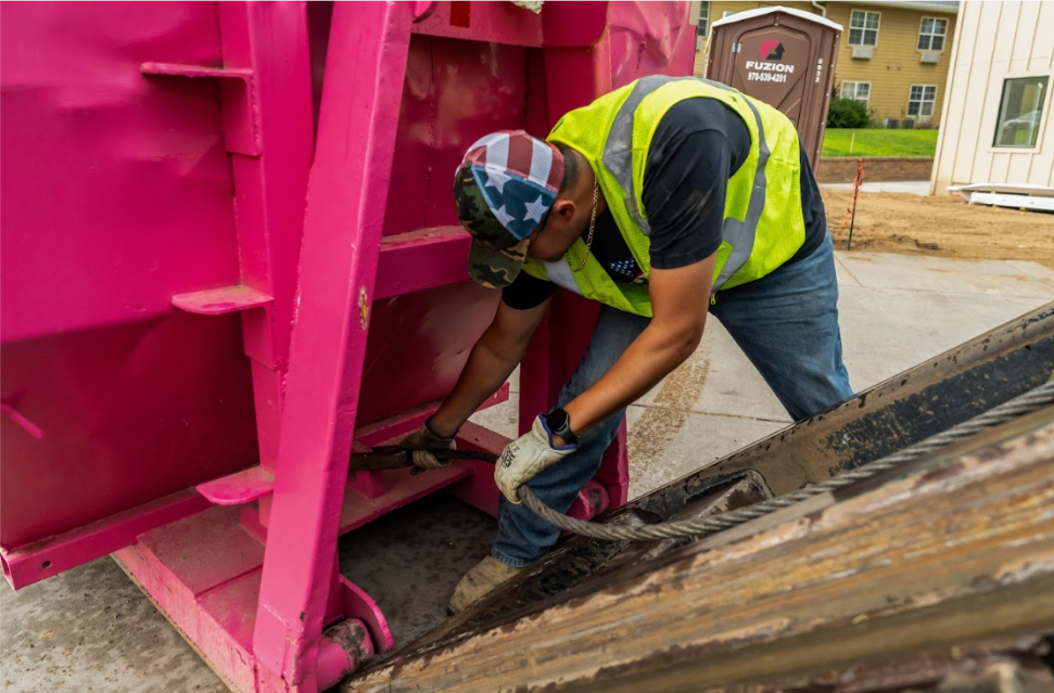 Fuzion team member securing a roll-off dumpster during delivery.