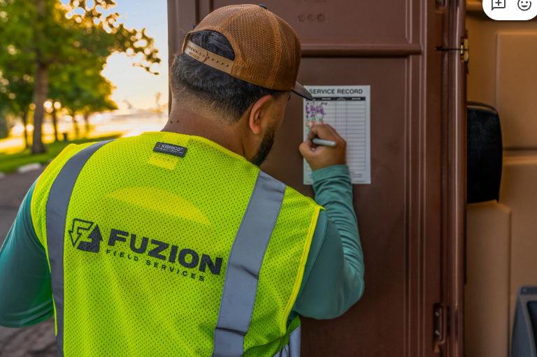 Fuzion technician completing a portable restroom service log.