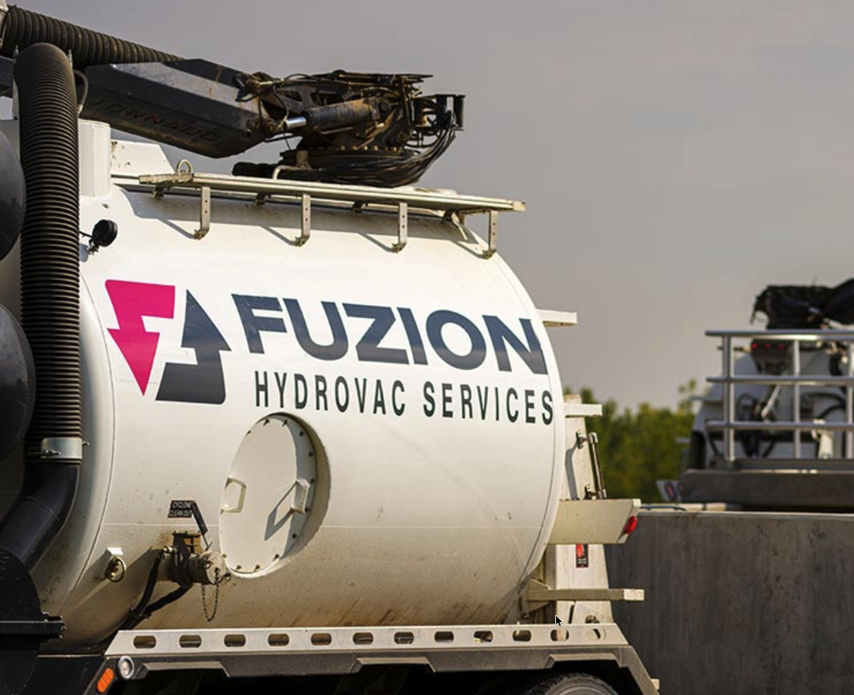 Close-up of a Fuzion Hydrovac Services truck parked at an industrial jobsite.