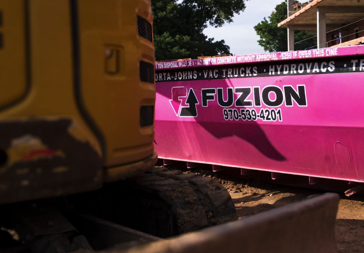 Fuzion roll-off dumpster positioned at an active construction site.