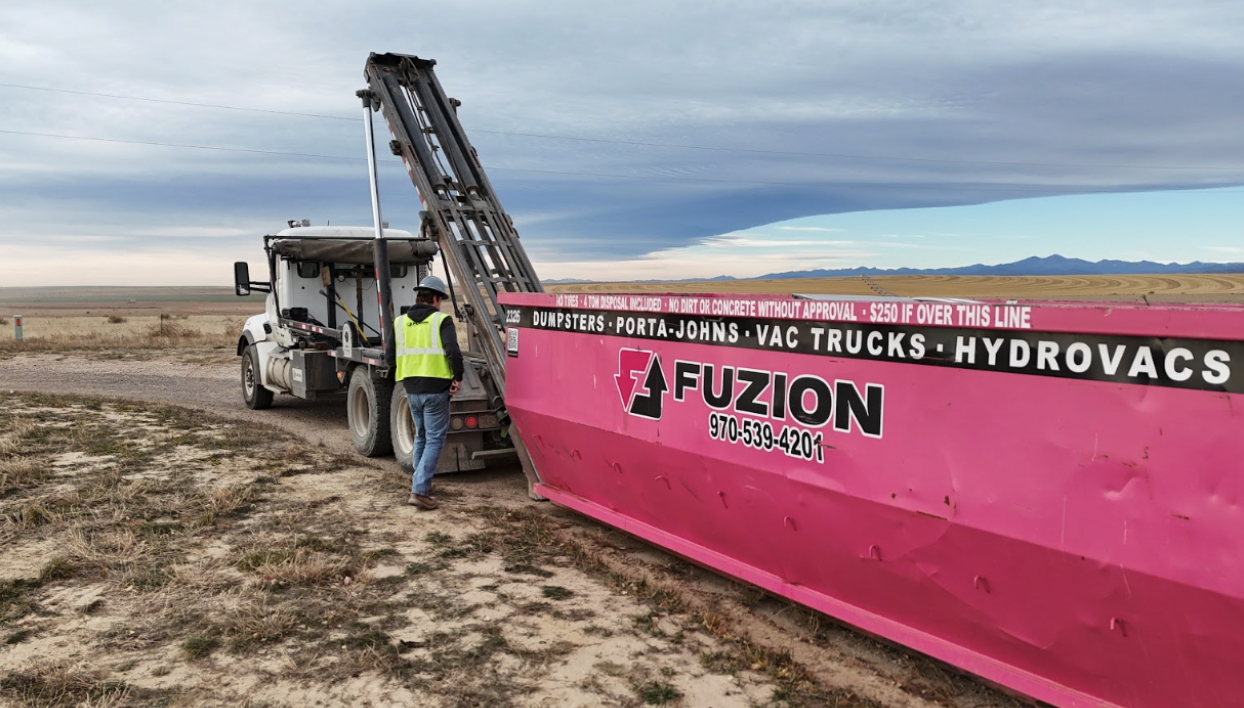 Fuzion roll-off dumpster being delivered at a job site.