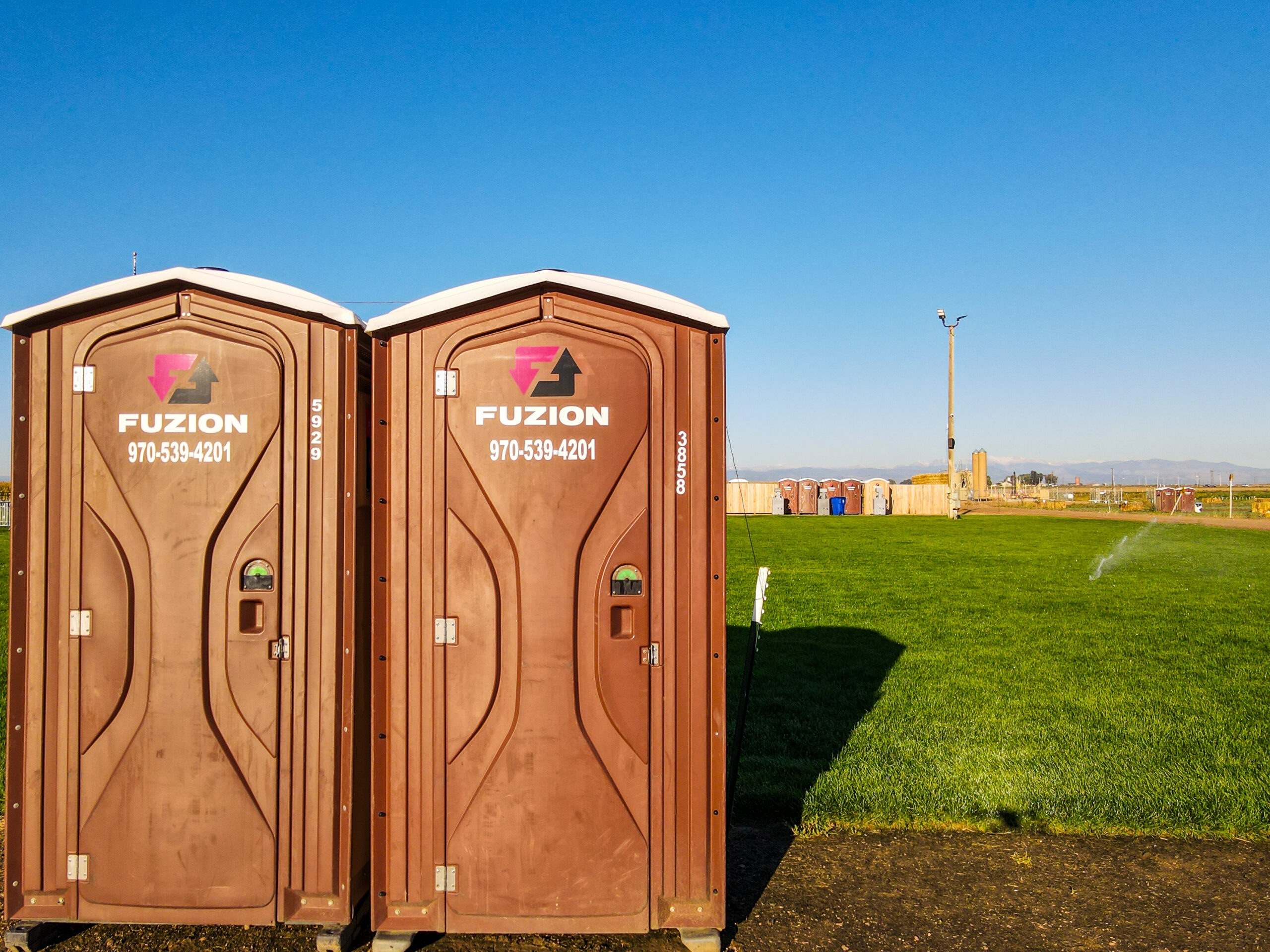 Two Fuzion portable restrooms set up at an outdoor venue.